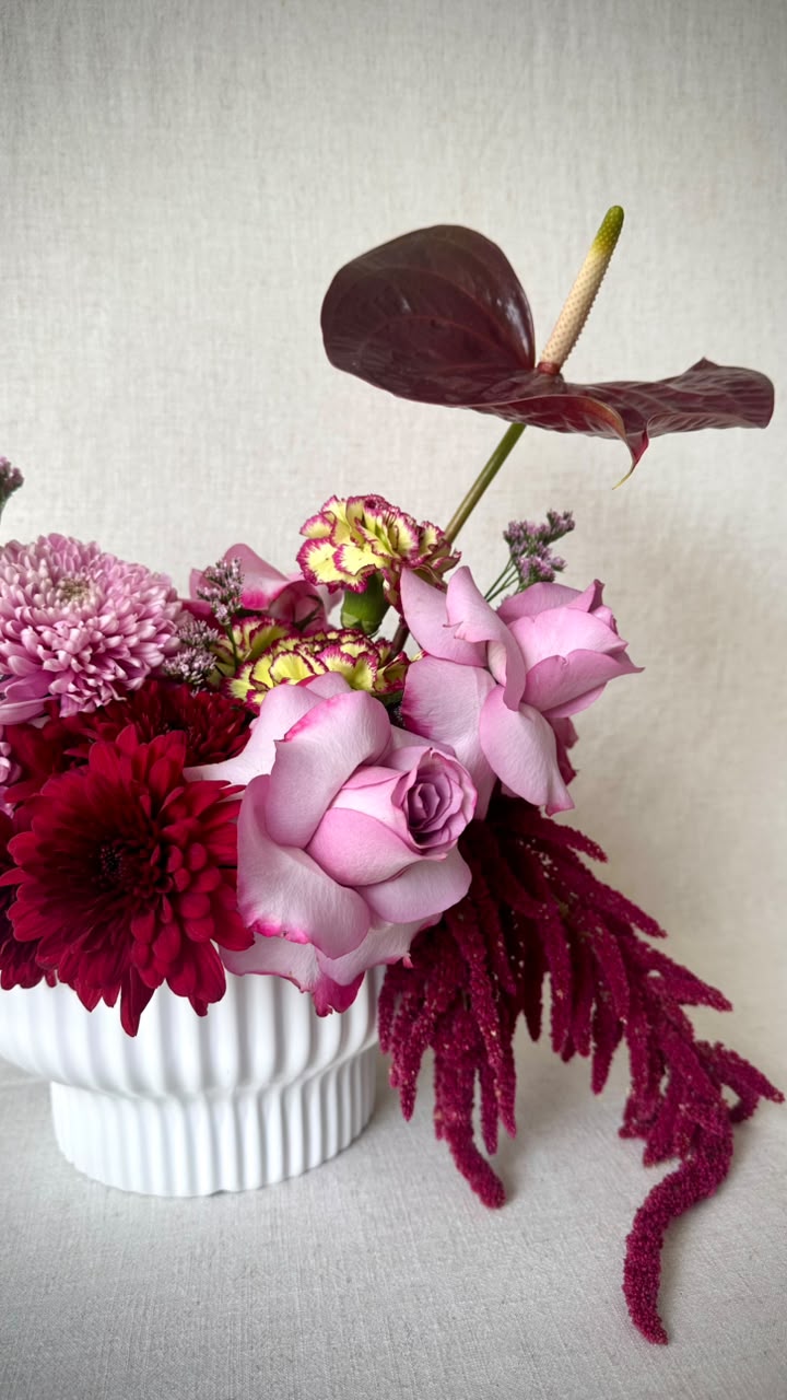 Romantic burgundy and pink arrangement with trailing red amaranthus in a white fluted vase